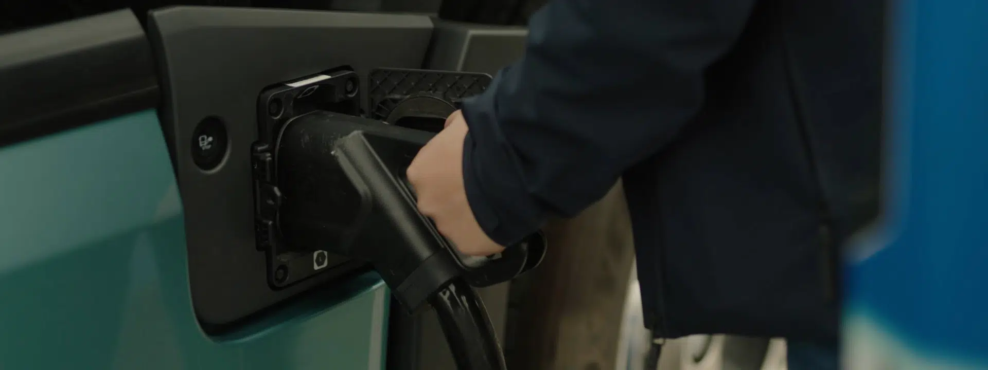 Close up image of person connecting EV charging cable to electric truck